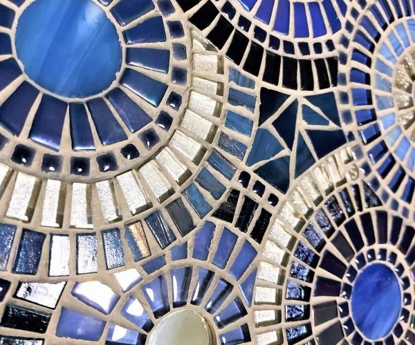 Vibrant mosaic tile design with blue, black, and white circular patterns.