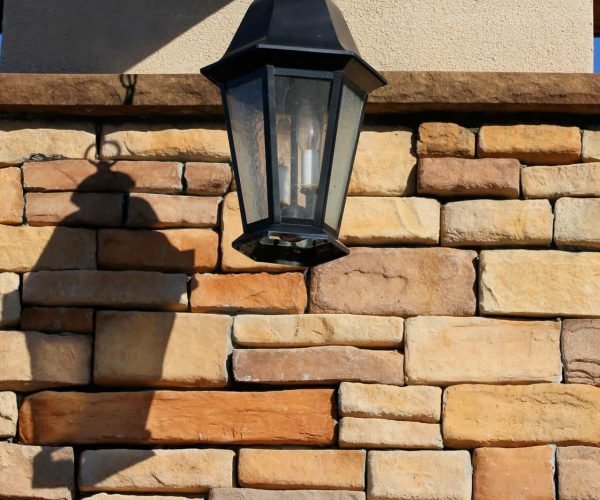 Stone wall with lantern light fixture for outdoor decor.