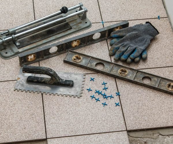 Tile installation tools including level, trowel, and gloves for home renovation.
